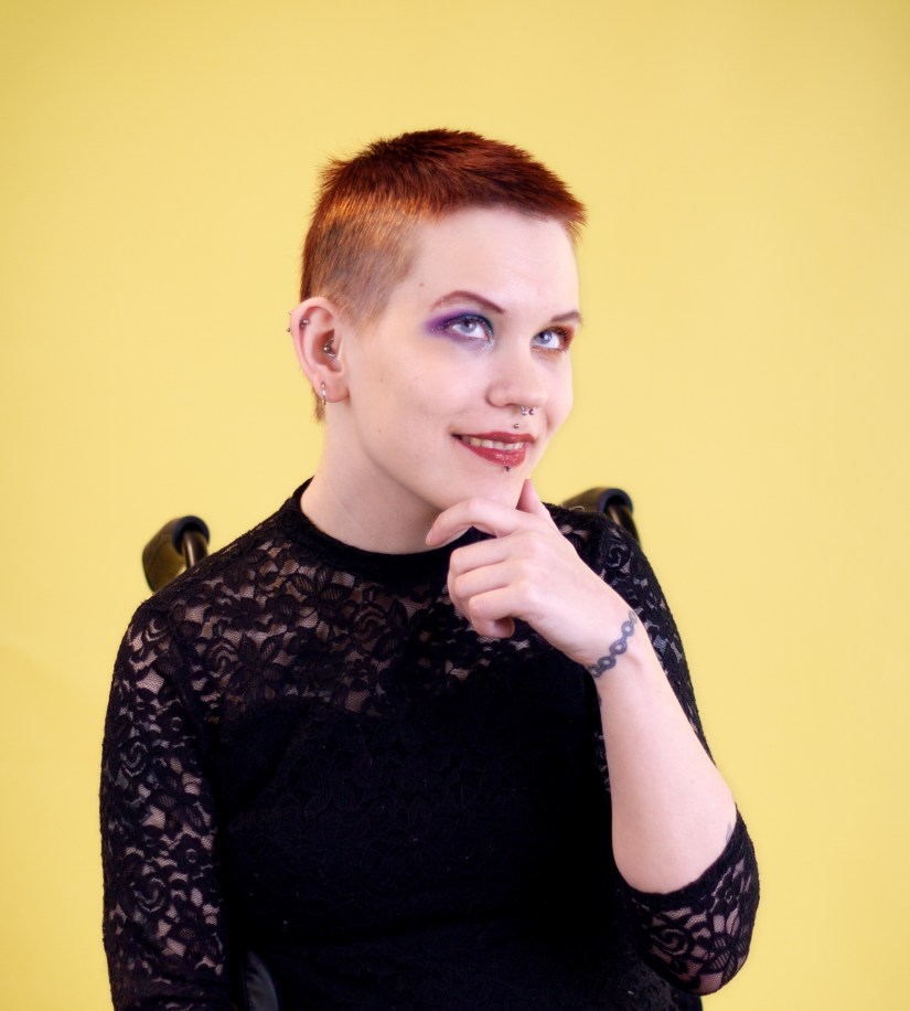 Pinja katsoo kameraa hymyillen, pohdiskelevassa poseerauksessa. 