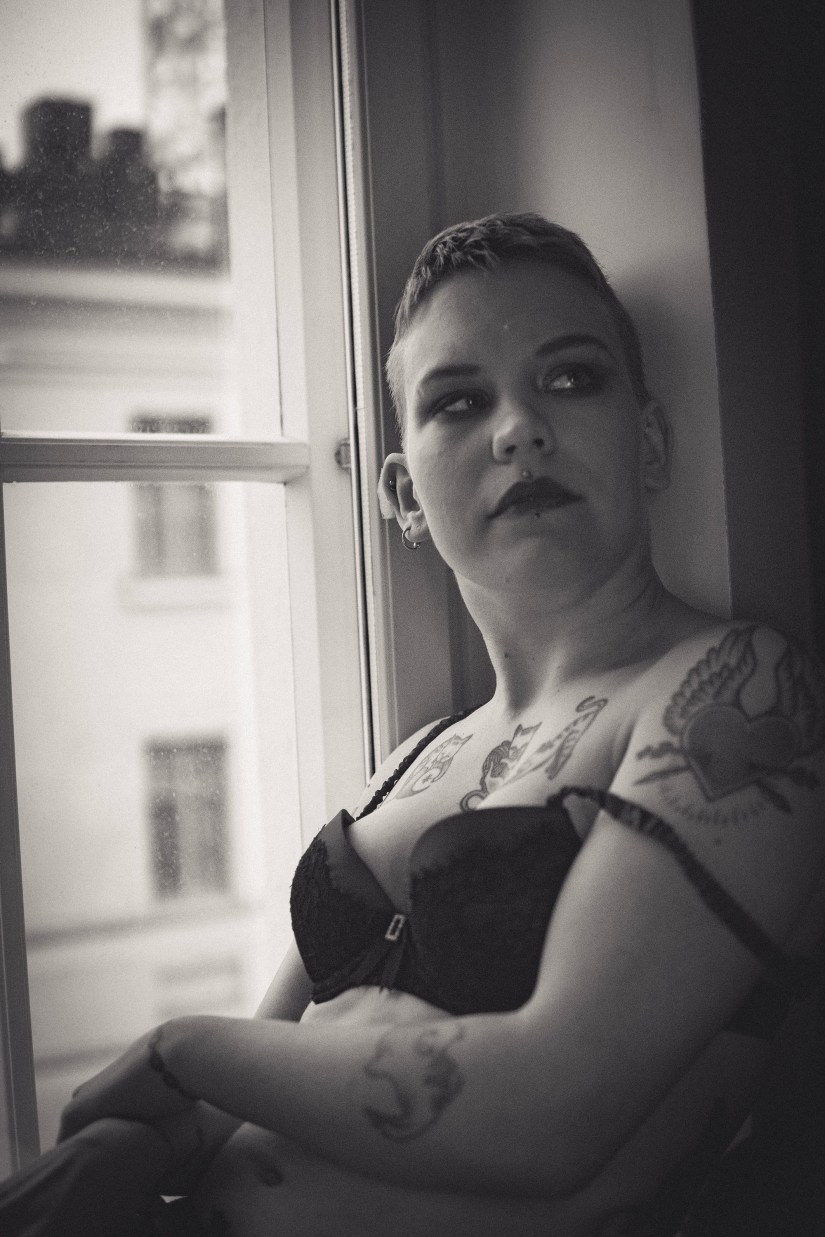 Nainen istuu ikkunalaudalla ja katselee sisään huoneeseen.