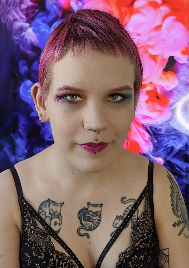 Pinja katsoo kameraan värikkään taustan edessä.