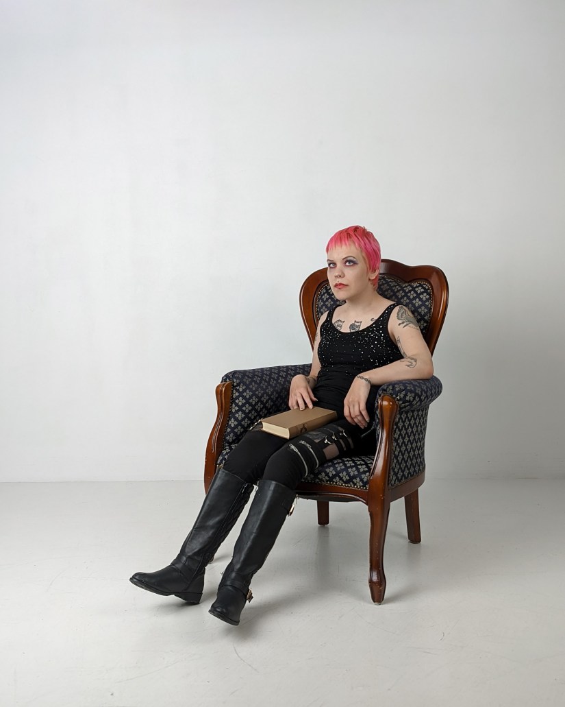 Pinja nojatuolissa kirja sylissään