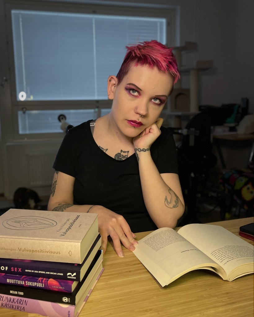 Pinja istuu pöydän ääressä lukemassa. Pöydällä on pinossa seksuaalisuusteemaisia kirjoja.