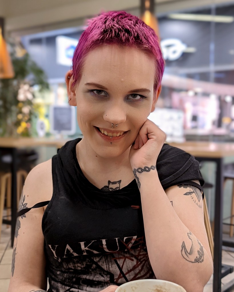 Pinja katsoo hymyillen kameraan kahvilassa.