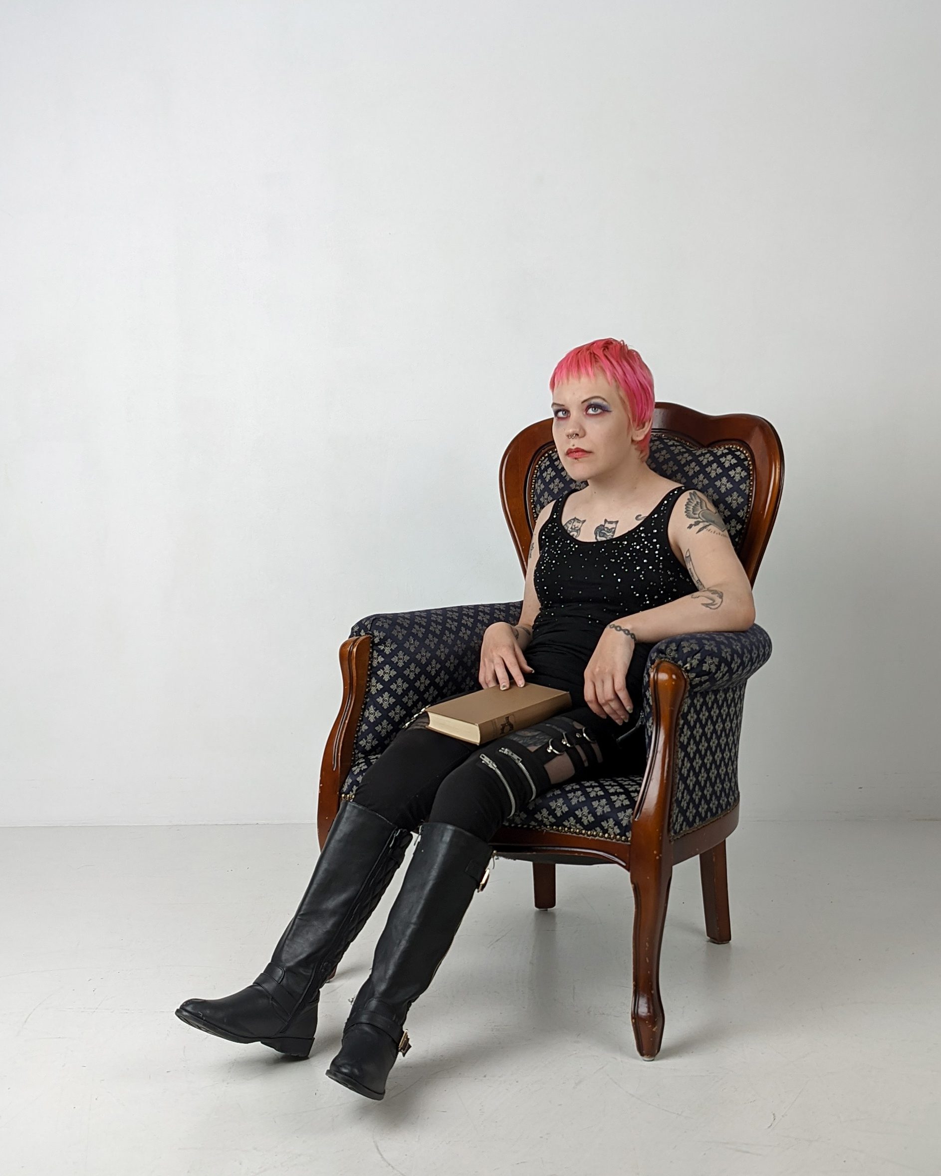 Pinja nojatuolissa kirja sylissään