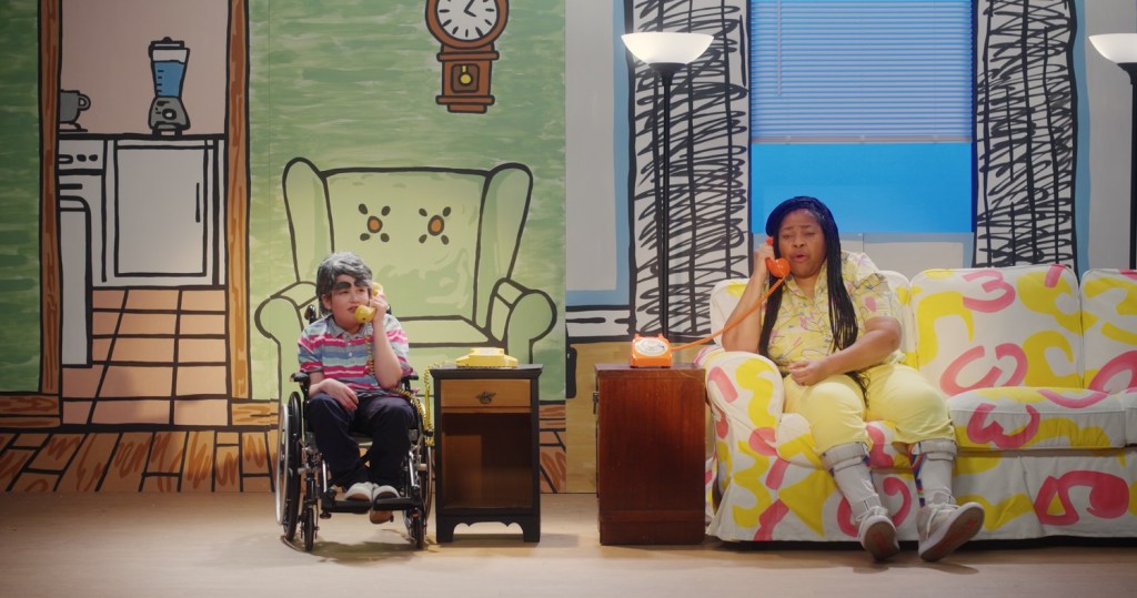 Menneisyyskuvaelmassa Patrice keskustelee värikkäissä, naivistisissa lavasteissa kumppaniaan Garyä näyttelevän pienen pojan kanssa.