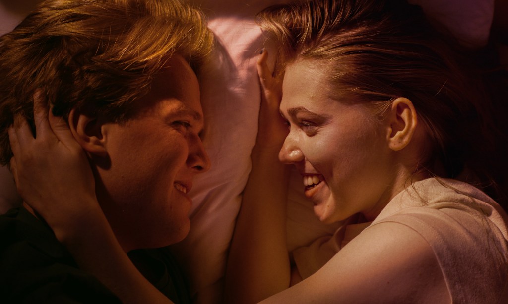 Ruutukaappauksessa elokuvasta My First Love päähenkilöt Oliver ja Ella makaavat aamuauringon valaisemalla sängyllä katsellen rakastavasti toisiaan silmiin.
